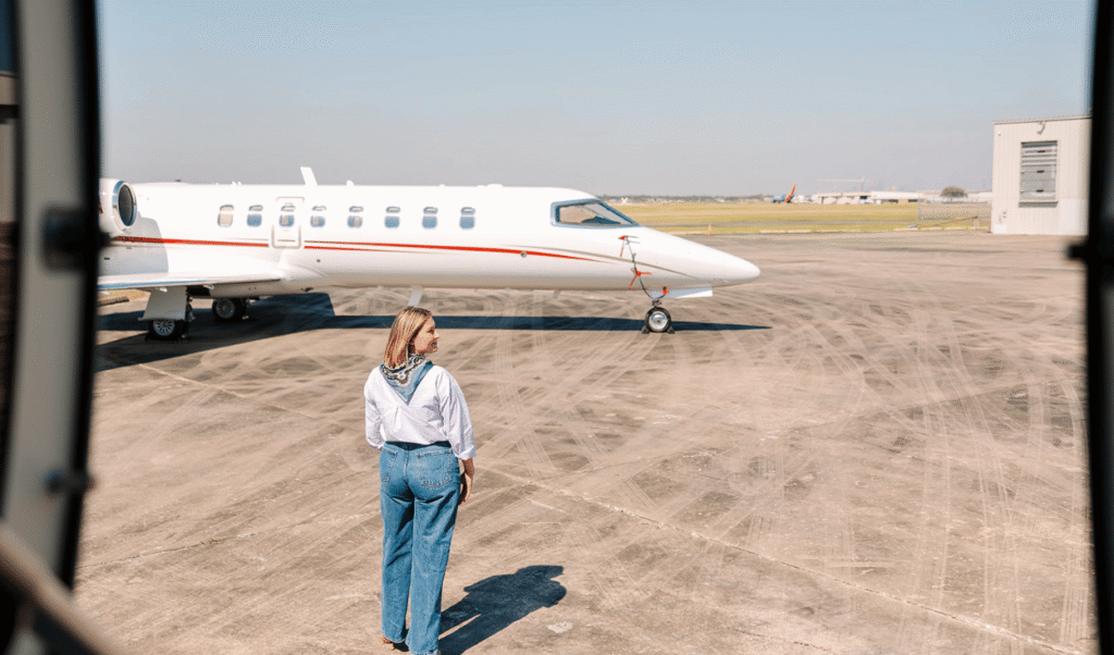 Houston Jet Direct private jet parked on airport runway with traveler walking toward aircraft