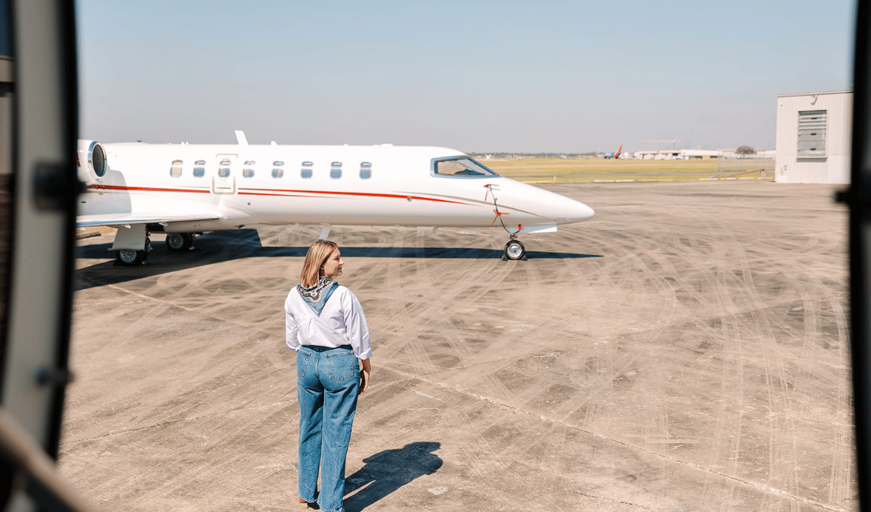Houston Jet Direct private jet parked on airport runway with traveler walking toward aircraft